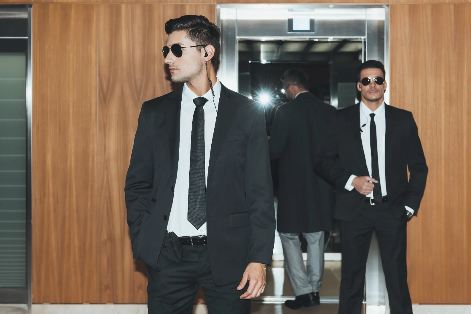 Plain-clothes protection agents escorting a principal through a lobby